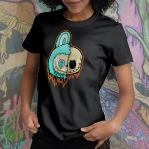 A t-shirt with a split-faced drippy Labubu character. One side is the turquoise-furred creature with large teal eyes, the other is a melting skull with a black eye socket. Orange and teal slime drips down the design.