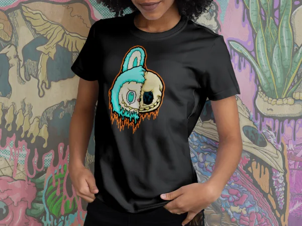 A t-shirt with a split-faced drippy Labubu character. One side is the turquoise-furred creature with large teal eyes, the other is a melting skull with a black eye socket. Orange and teal slime drips down the design.