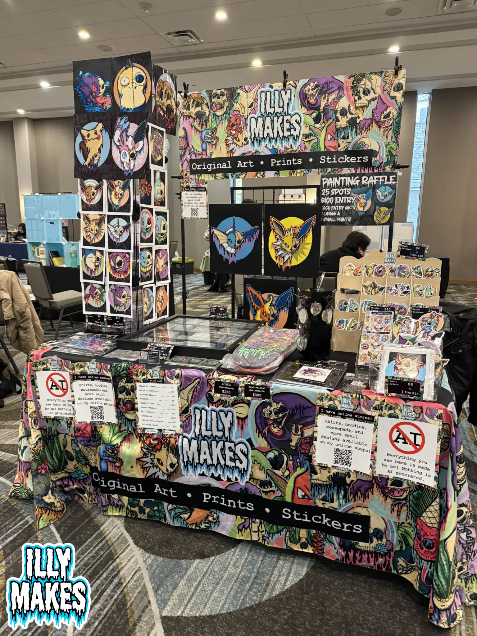 My illymakes booth at KinshokuCon with drippy skull art, prints, stickers, and original paintings.